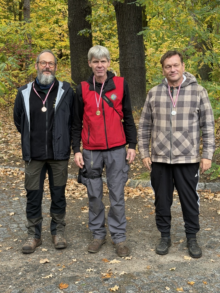 Drei Medaillenträger vor herbstlichen Bäumen bei der KM 3D am 17. Oktober 2026